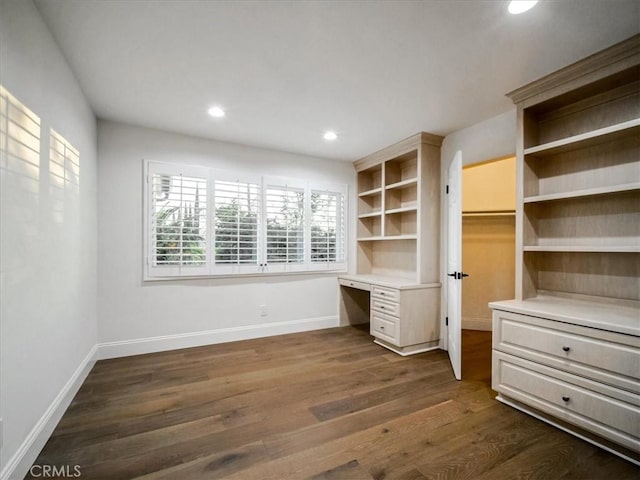 unfurnished office featuring dark wood-type flooring and built in desk