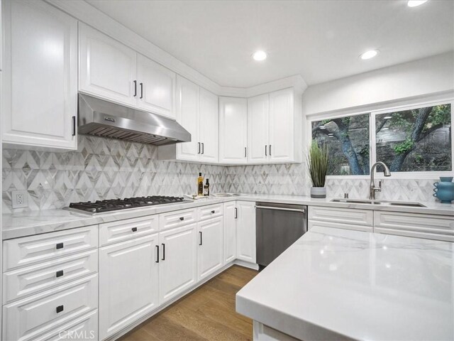 kitchen featuring sink, white cabinetry, dark hardwood / wood-style flooring, stainless steel appliances, and backsplash