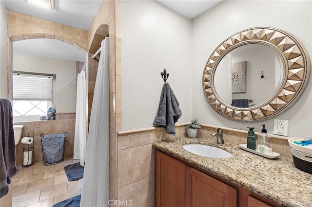 bathroom featuring vanity and tile walls