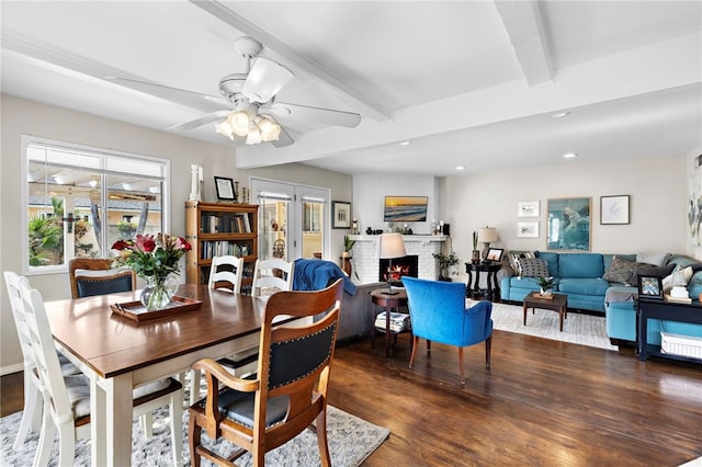 dining space featuring beamed ceiling, ceiling fan, dark hardwood / wood-style floors, and a fireplace