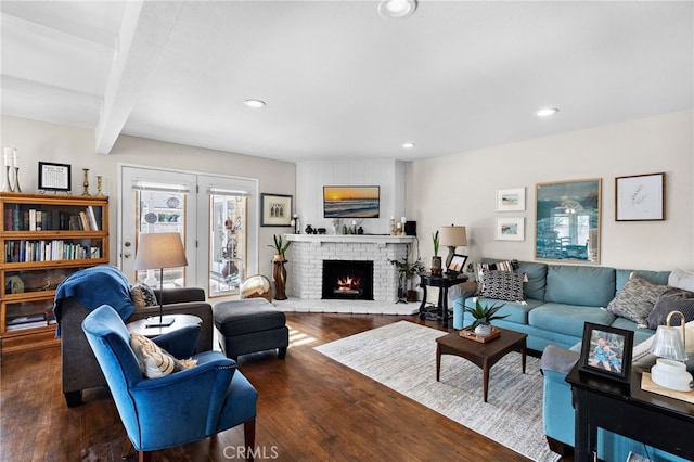 living room featuring beam ceiling, dark hardwood / wood-style floors, and a fireplace