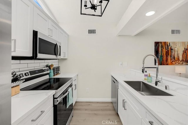 kitchen featuring white cabinetry, appliances with stainless steel finishes, sink, and light stone counters