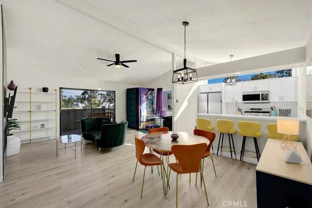 dining space featuring ceiling fan with notable chandelier, lofted ceiling with beams, and light hardwood / wood-style flooring