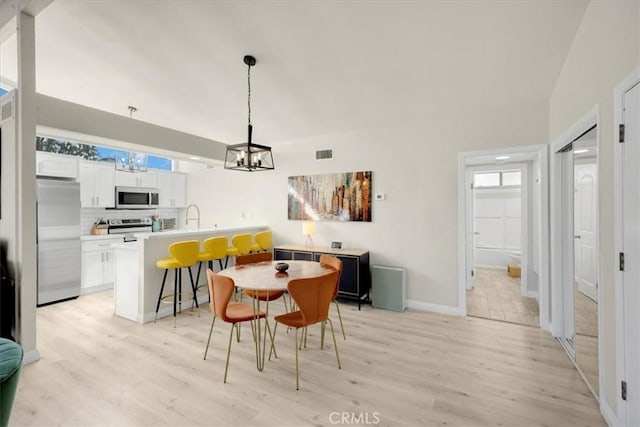 dining room featuring sink, light hardwood / wood-style flooring, and a chandelier