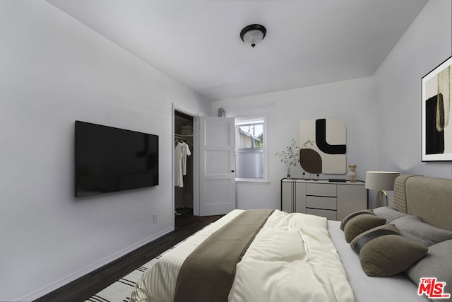 bedroom featuring dark hardwood / wood-style flooring and a spacious closet