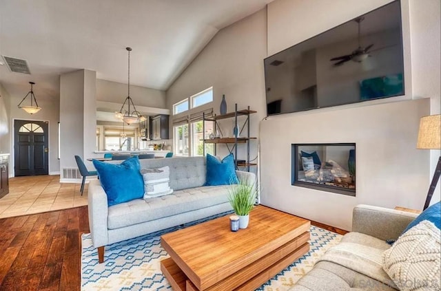 living room with high vaulted ceiling and light wood-type flooring