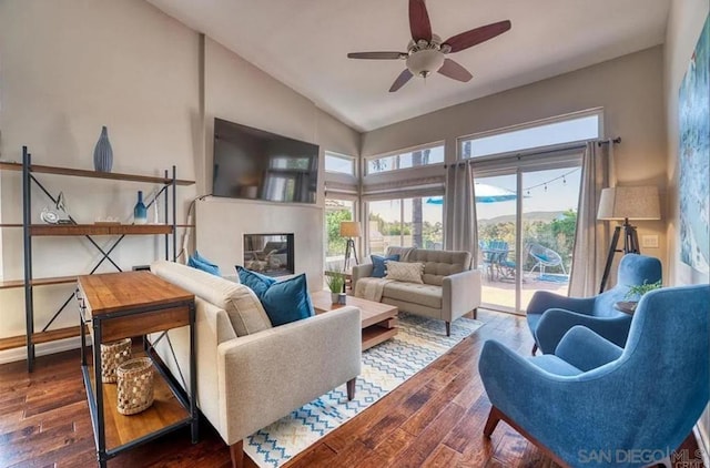 living room with dark wood-type flooring, ceiling fan, and vaulted ceiling