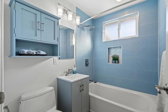 full bathroom featuring vanity, tiled shower / bath combo, and toilet