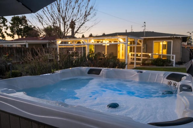 pool at dusk with a hot tub