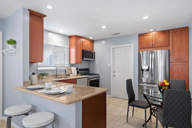 kitchen with light tile patterned flooring, sink, a breakfast bar area, appliances with stainless steel finishes, and kitchen peninsula