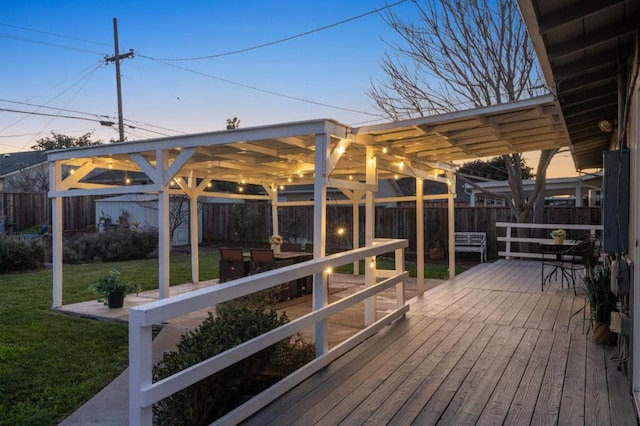 deck at dusk featuring a yard