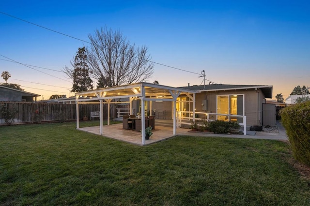 back house at dusk with a yard and a patio area