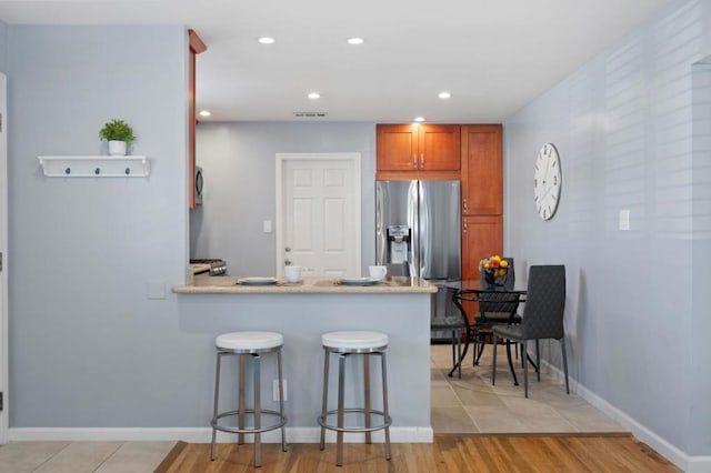 kitchen featuring appliances with stainless steel finishes, a breakfast bar area, light wood-type flooring, and kitchen peninsula