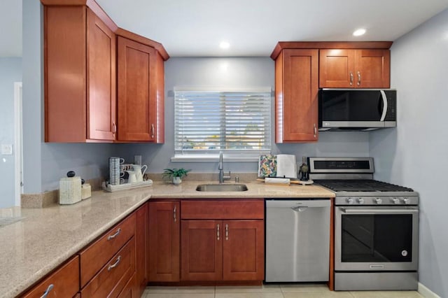 kitchen with appliances with stainless steel finishes, sink, and light stone counters