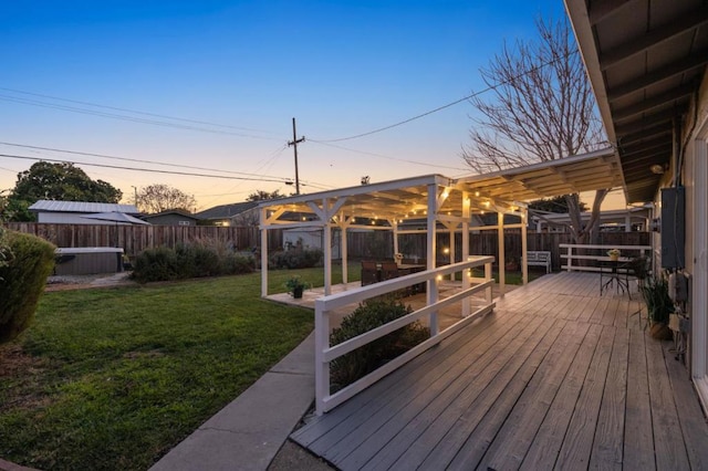 deck at dusk with a yard, a pergola, and a jacuzzi