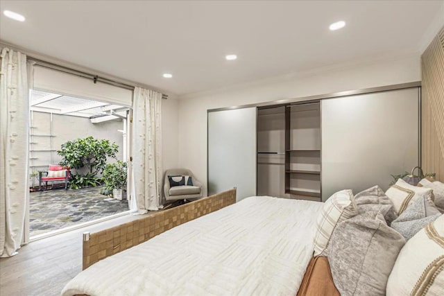 bedroom with multiple windows, hardwood / wood-style floors, crown molding, and access to outside