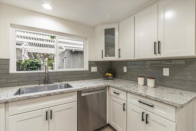 kitchen featuring sink, white cabinetry, tasteful backsplash, light stone countertops, and stainless steel dishwasher