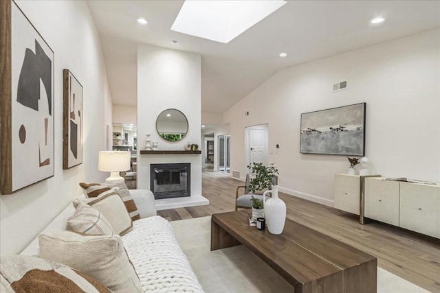 living room featuring light hardwood / wood-style floors and vaulted ceiling with skylight