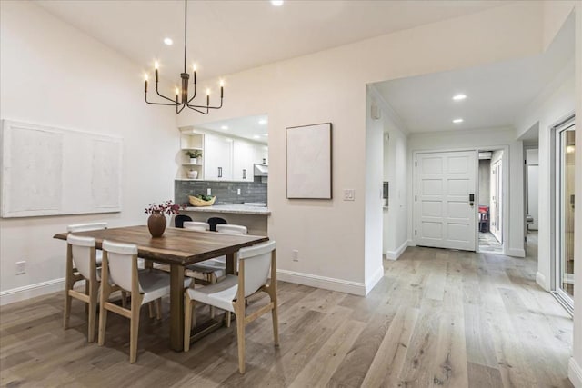 dining area with light hardwood / wood-style flooring and a notable chandelier