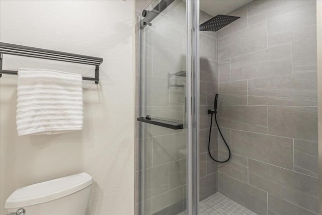 bathroom featuring a shower with shower door and toilet