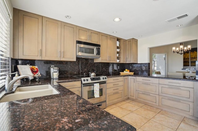 kitchen with appliances with stainless steel finishes, decorative light fixtures, tasteful backsplash, sink, and light brown cabinets