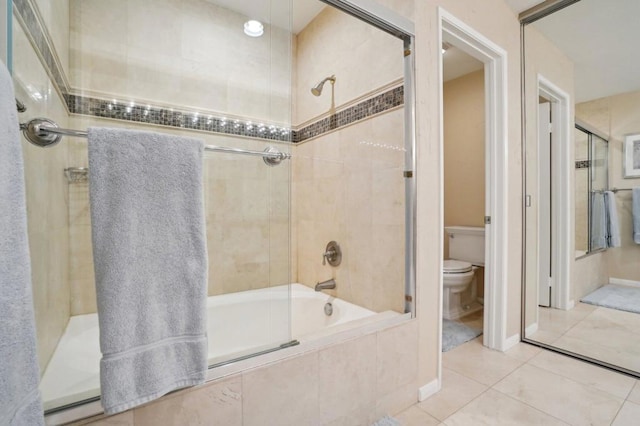 bathroom with bath / shower combo with glass door, tile patterned floors, and toilet