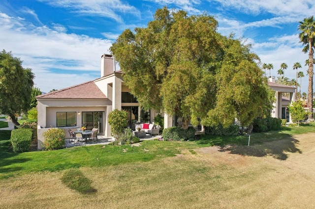 rear view of property featuring a yard, outdoor lounge area, and a patio