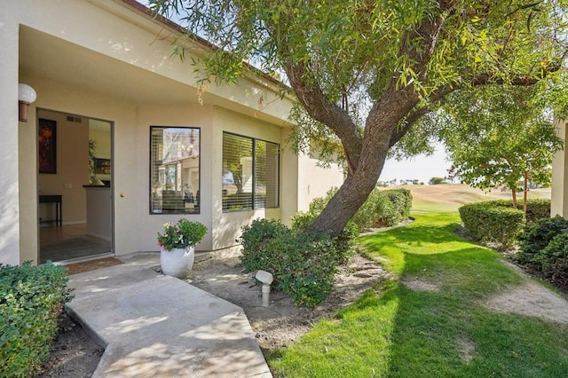 view of exterior entry featuring a patio and a lawn