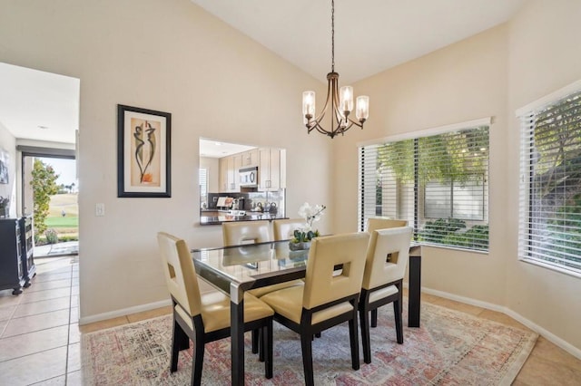 tiled dining space featuring a chandelier and high vaulted ceiling