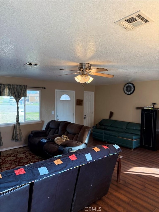 living room featuring hardwood / wood-style flooring, ceiling fan, and a textured ceiling