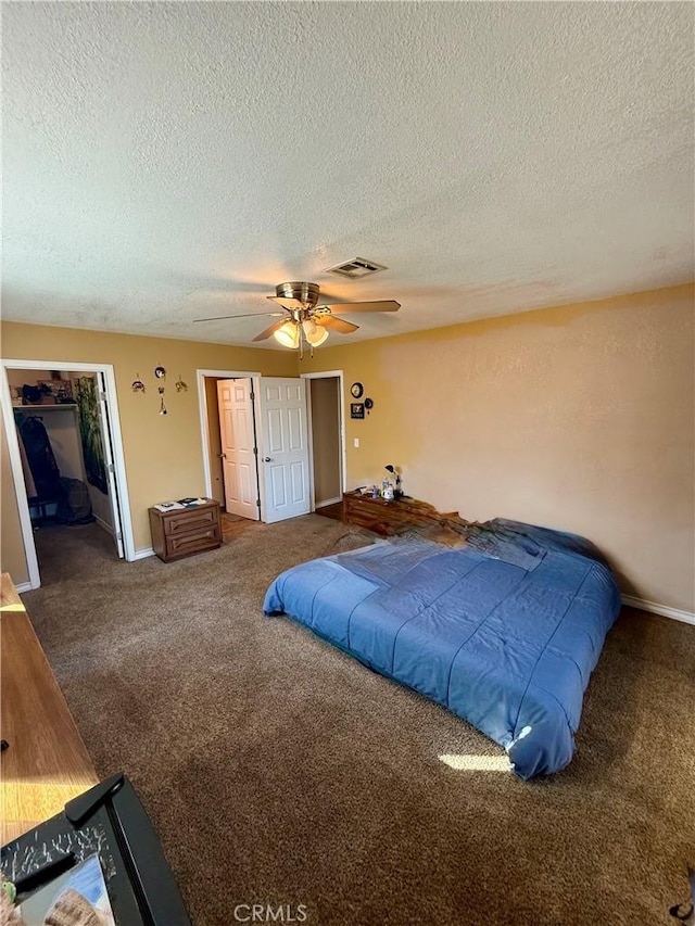 carpeted bedroom with ceiling fan, a textured ceiling, and multiple closets