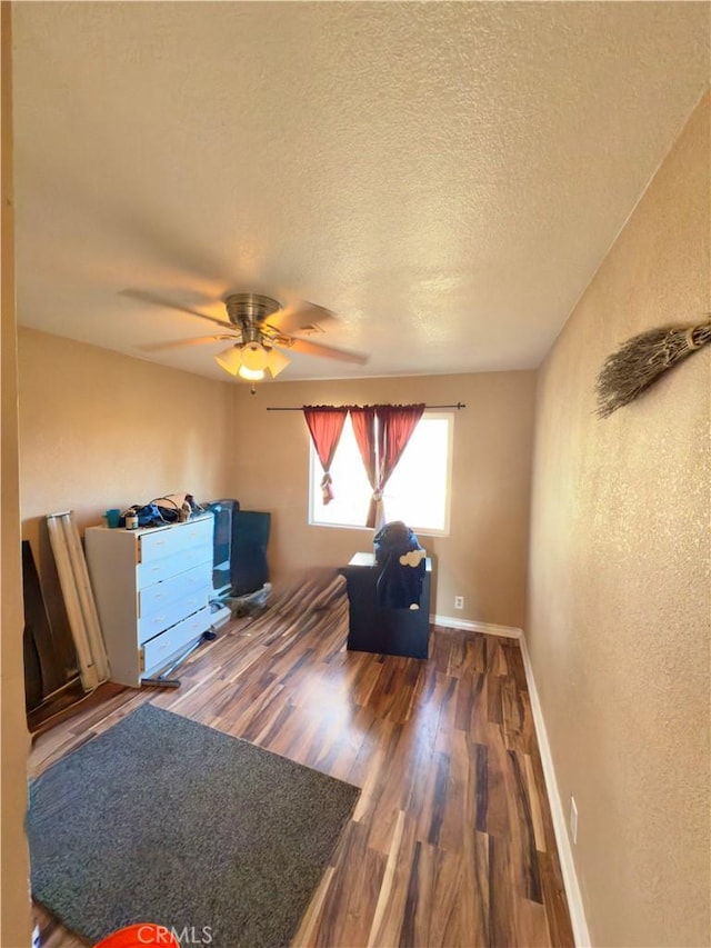 interior space with dark wood-type flooring, ceiling fan, and a textured ceiling