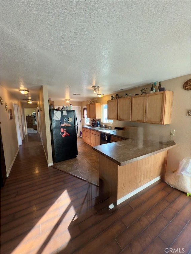 kitchen with dark hardwood / wood-style floors, kitchen peninsula, a textured ceiling, and black appliances