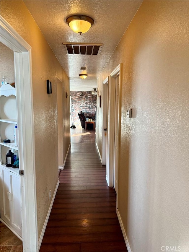 corridor with dark hardwood / wood-style flooring and a textured ceiling