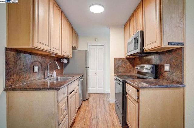 kitchen featuring light brown cabinetry, sink, backsplash, stainless steel appliances, and light wood-type flooring