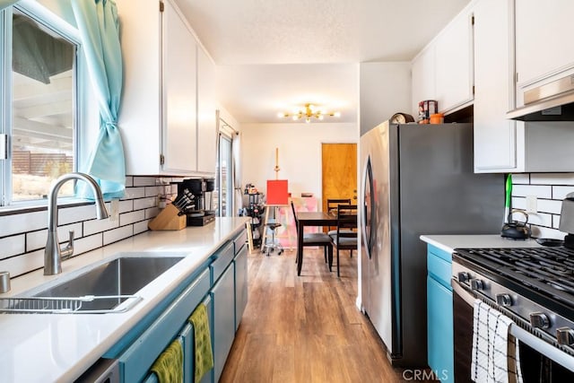 kitchen featuring sink, stainless steel range with gas stovetop, tasteful backsplash, white cabinets, and light wood-type flooring