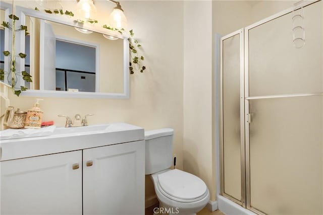 bathroom featuring a shower with door, vanity, and toilet