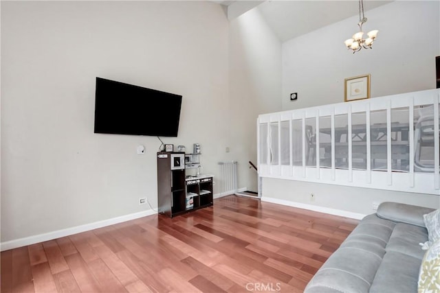 living room with hardwood / wood-style flooring, high vaulted ceiling, and an inviting chandelier