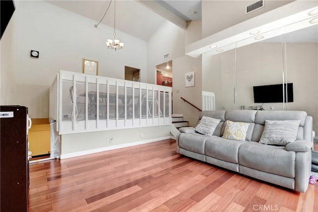 living room featuring hardwood / wood-style flooring, high vaulted ceiling, an inviting chandelier, and beam ceiling