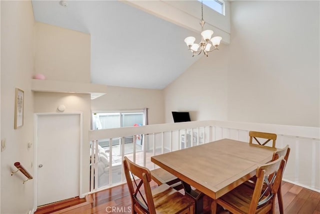 dining room with an inviting chandelier, hardwood / wood-style floors, and high vaulted ceiling