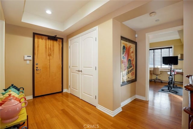 hall featuring a tray ceiling and light hardwood / wood-style flooring