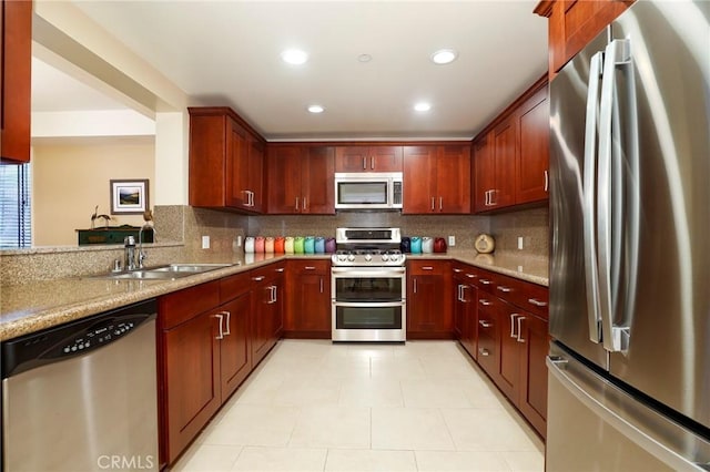 kitchen featuring light stone counters, stainless steel appliances, sink, and decorative backsplash