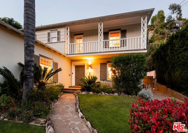 view of front of home with a balcony and a front lawn