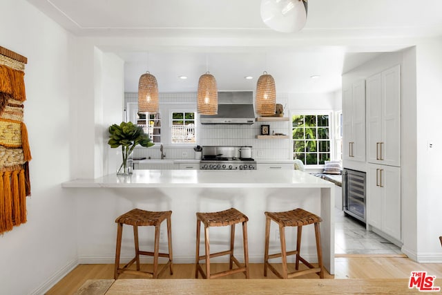 kitchen with white cabinetry, decorative light fixtures, a kitchen breakfast bar, and kitchen peninsula