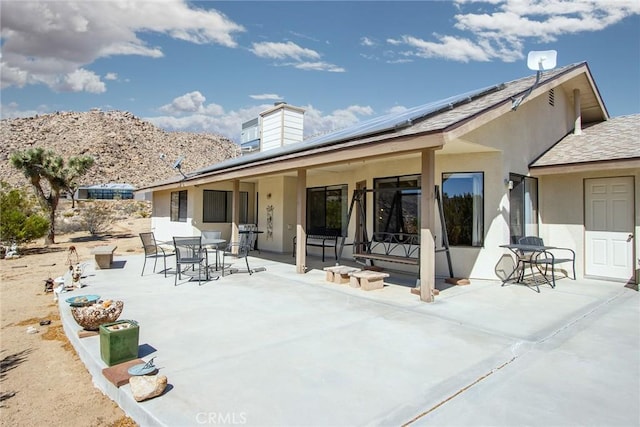 rear view of property with a mountain view, a patio, and solar panels