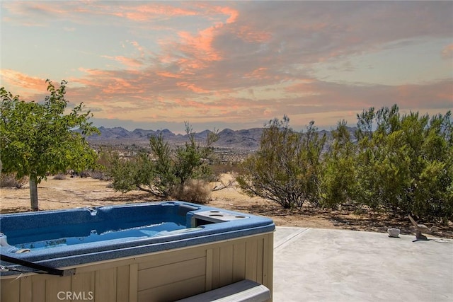 patio terrace at dusk with a mountain view and a hot tub