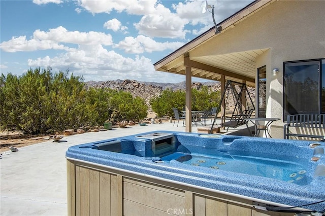 view of swimming pool with a hot tub, a patio, and a mountain view