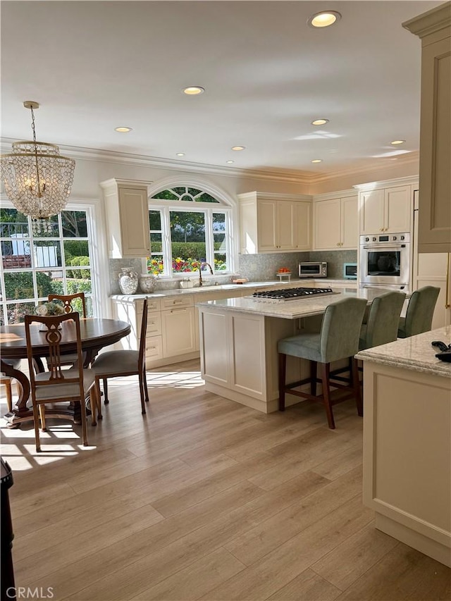 kitchen featuring hanging light fixtures, stainless steel appliances, a center island, ornamental molding, and a healthy amount of sunlight