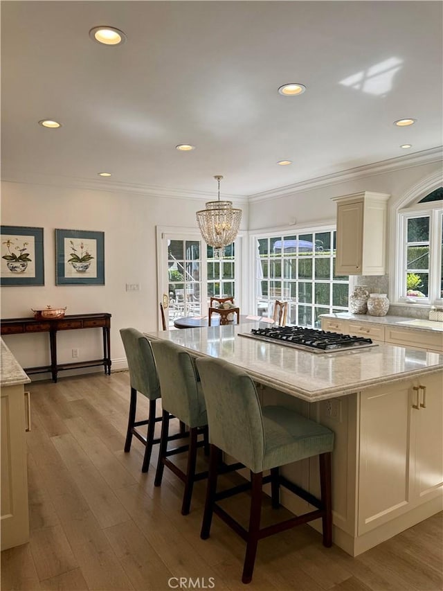 kitchen featuring hanging light fixtures, ornamental molding, stainless steel gas stovetop, and a kitchen island