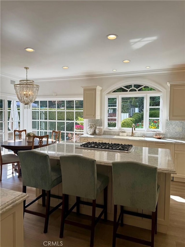 kitchen featuring light stone counters, hanging light fixtures, a center island, and stainless steel gas cooktop